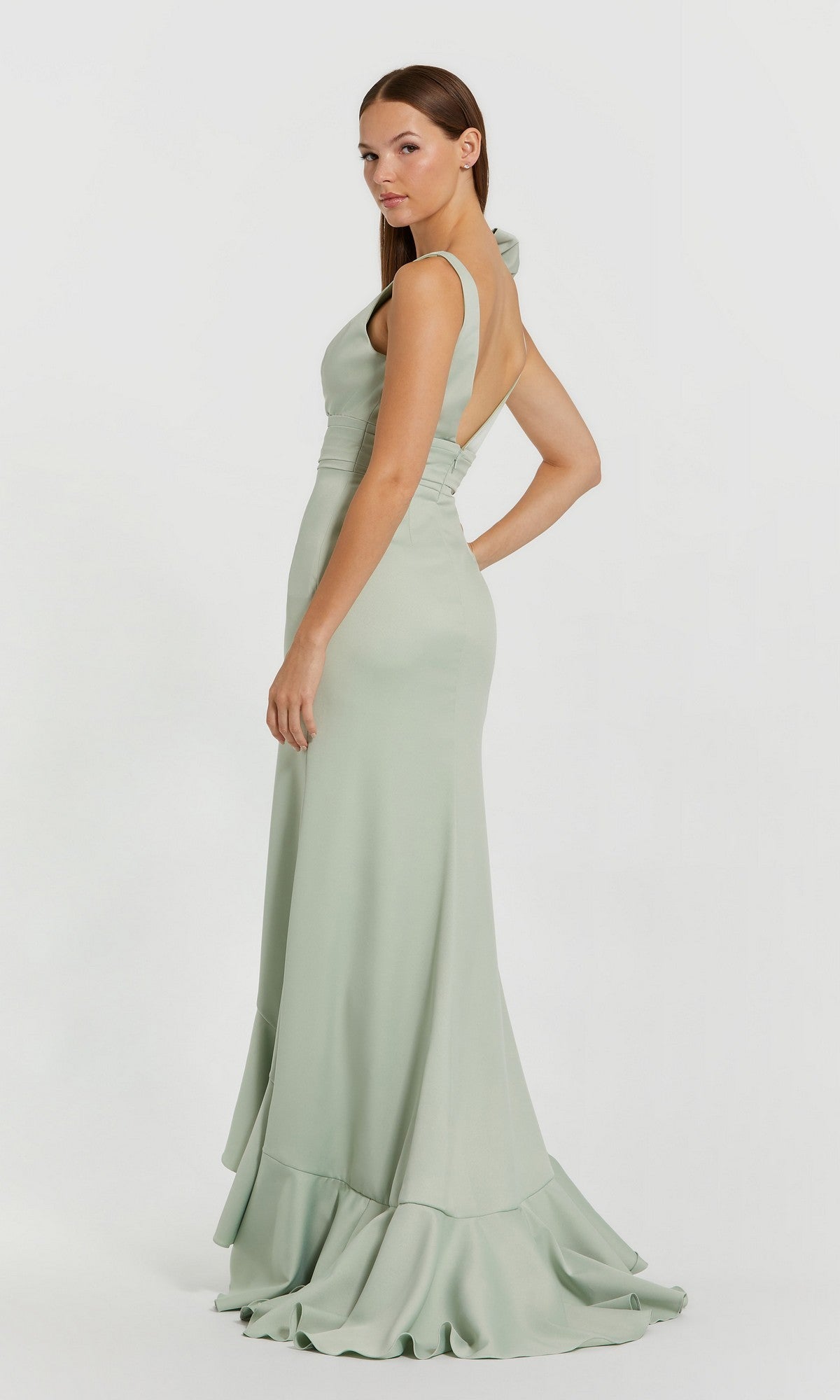 Woman in a light green, floor-length, sleeveless gown with a fitted waist and ruffled hem, standing against a plain white background—a graceful Long Formal Dress: Mac Duggal 49965, perfect for any elegant occasion.